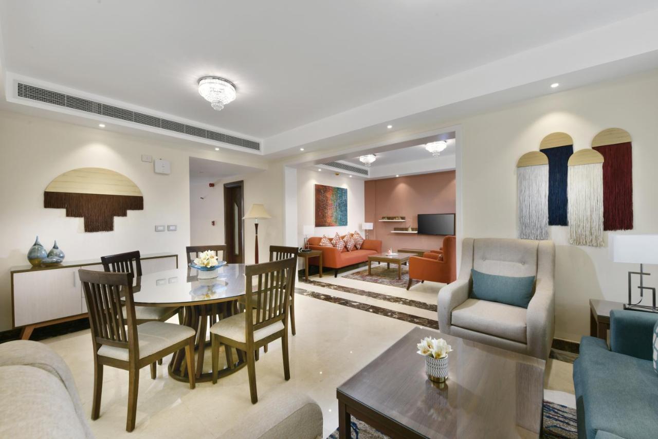 Tolip Resort El Galala Majestic Ain Sukhna Ngoại thất bức ảnh The photo shows a modern living room space that is elegantly designed. It features a seating area with a comfortable sofa and armchairs, complemented by a decorative coffee table. There is a dining table with several wooden chairs, providing a cozy a