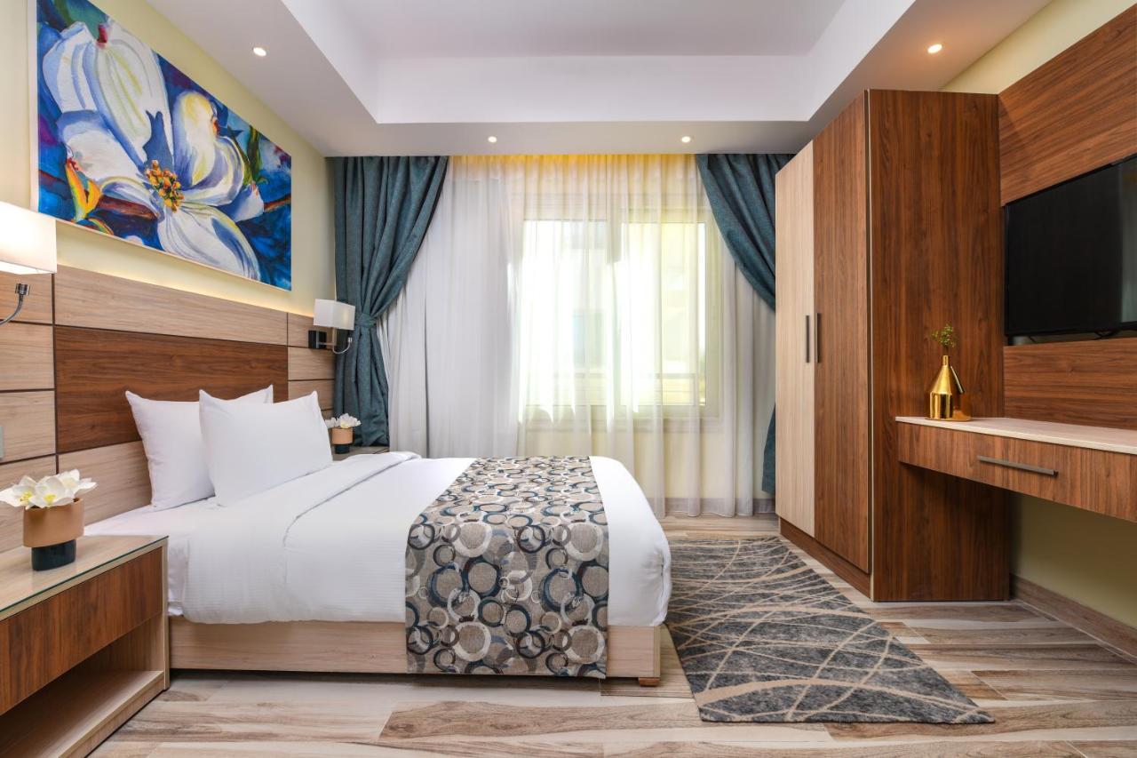 Tolip Resort El Galala Majestic Ain Sukhna Ngoại thất bức ảnh The photo shows a well-designed hotel room. It features a comfortable bed with a decorative bedspread and two pillows. There are soft curtains framing a window that lets in natural light. On one side, there is a colorful piece of artwork hanging on t