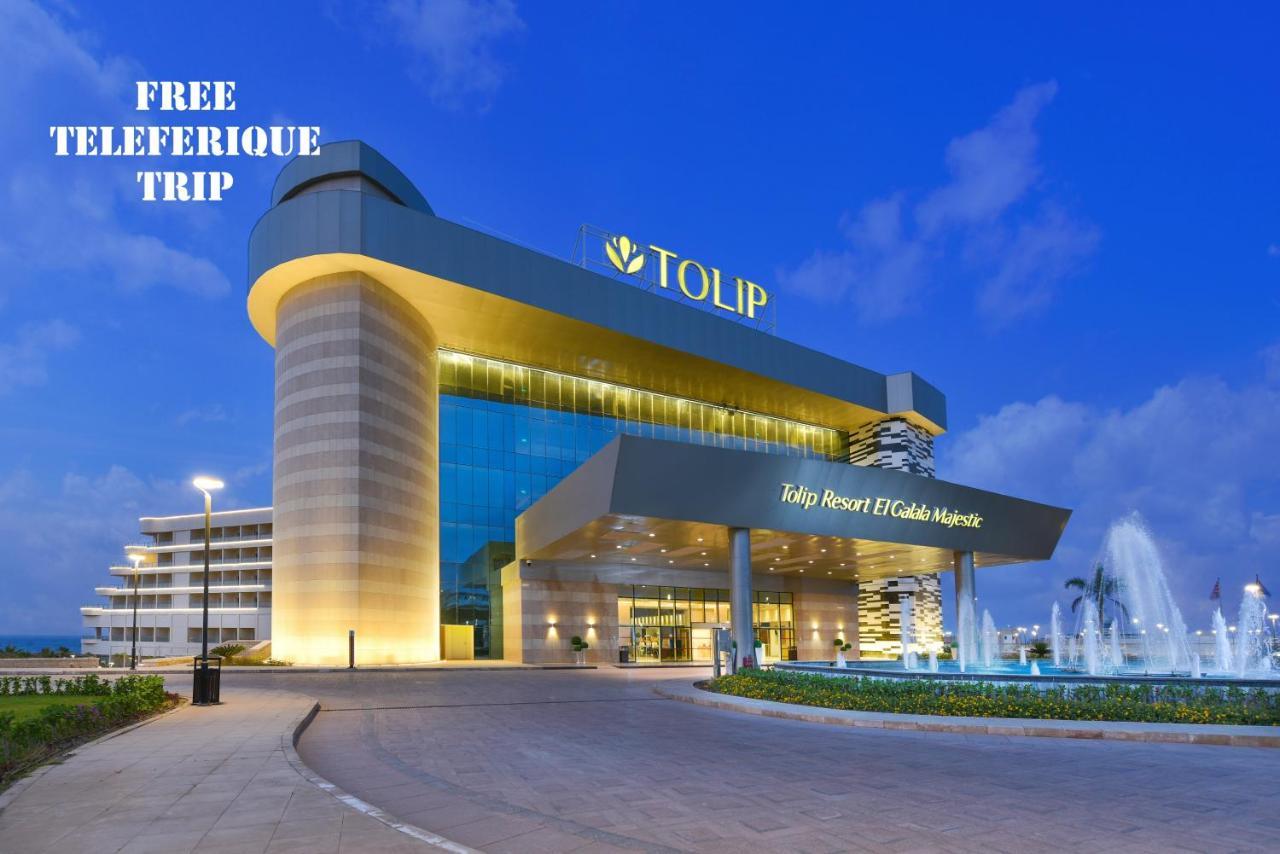 Tolip Resort El Galala Majestic Ain Sukhna Ngoại thất bức ảnh The photo shows a modern hotel building named "Tolip Resort & Spa," featuring a sleek architectural design with large glass windows. The hotel is illuminated against a twilight sky, showcasing its prominent signage. In the foreground, there is a well