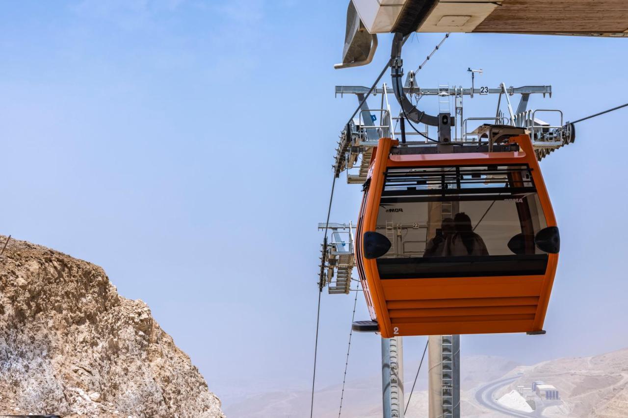 Tolip Resort El Galala Majestic Ain Sukhna Ngoại thất bức ảnh The photo shows an orange gondola or cable car hanging on a cable system. The gondola appears to be suspended in the air above a rocky landscape, with a clear sky in the background. There are supporting cables and structures visible, indicating that 