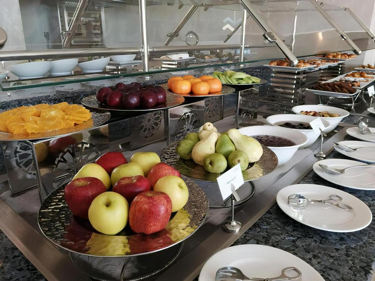 Tolip Resort El Galala Majestic Ain Sukhna Ngoại thất bức ảnh The photo displays a buffet setup featuring an assortment of fresh fruits arranged on several tiered trays. There are red and green apples, pears, grapes, and oranges. Adjacent to the fruit display, there are several bowls containing various other fo