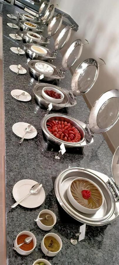 Tolip Resort El Galala Majestic Ain Sukhna Ngoại thất bức ảnh The photo shows a buffet setup featuring multiple metal serving trays on a dark granite countertop. One tray contains circular slices of food, possibly sausages or a similar dish, while another bowl holds what appears to be red food items, though it'