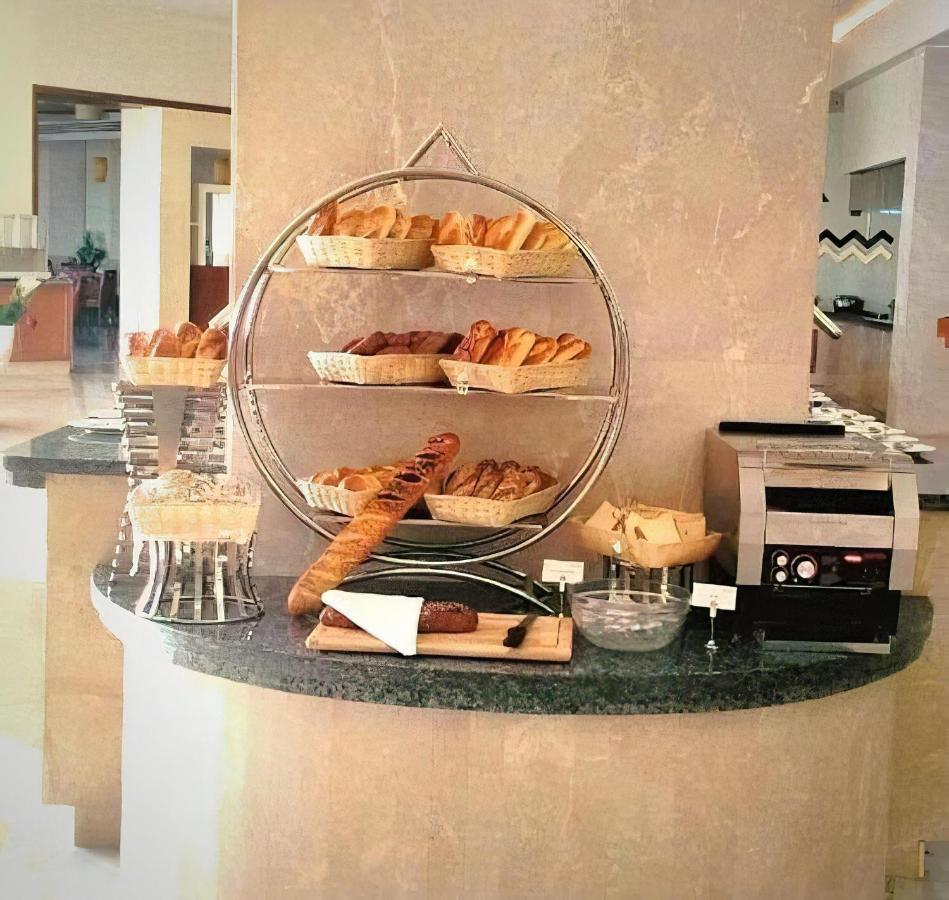 Tolip Resort El Galala Majestic Ain Sukhna Ngoại thất bức ảnh The photo shows a display of various types of bread and pastries arranged on a countertop. There are several baskets stacked on a circular stand, filled with different baked goods like croissants and rolls. A long baguette is placed horizontally on a